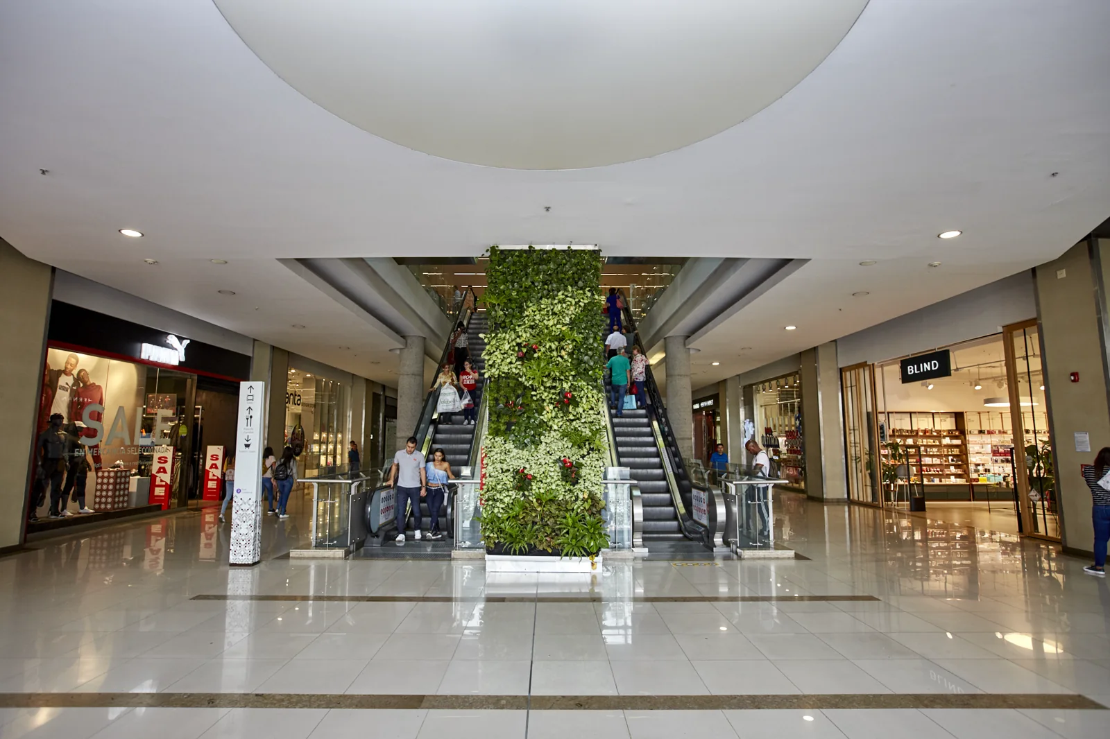 Interior real de Parque Arboleda con escalera eléctrica y jardín vertical